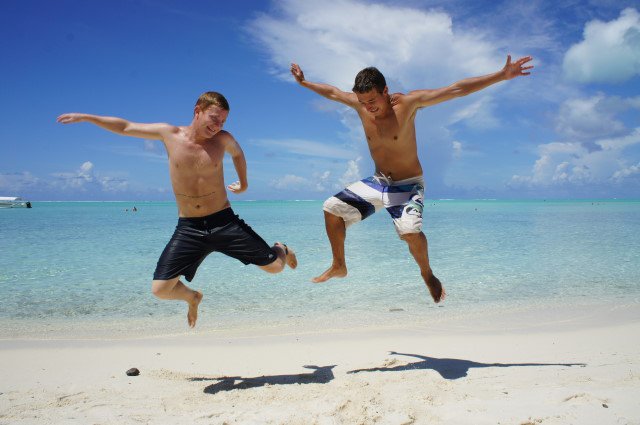 Roy and a friend jumping on a sunny beach, the benefits of working remotely 